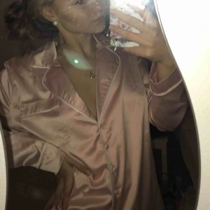  - Pyjamasskjorta i rosa ”siden” material. Fick den i julklapp förra året men har aldrig kommit till användning, så jättebra skick. Går även att använda som vanlig skjorta. Köparen står för frakt 