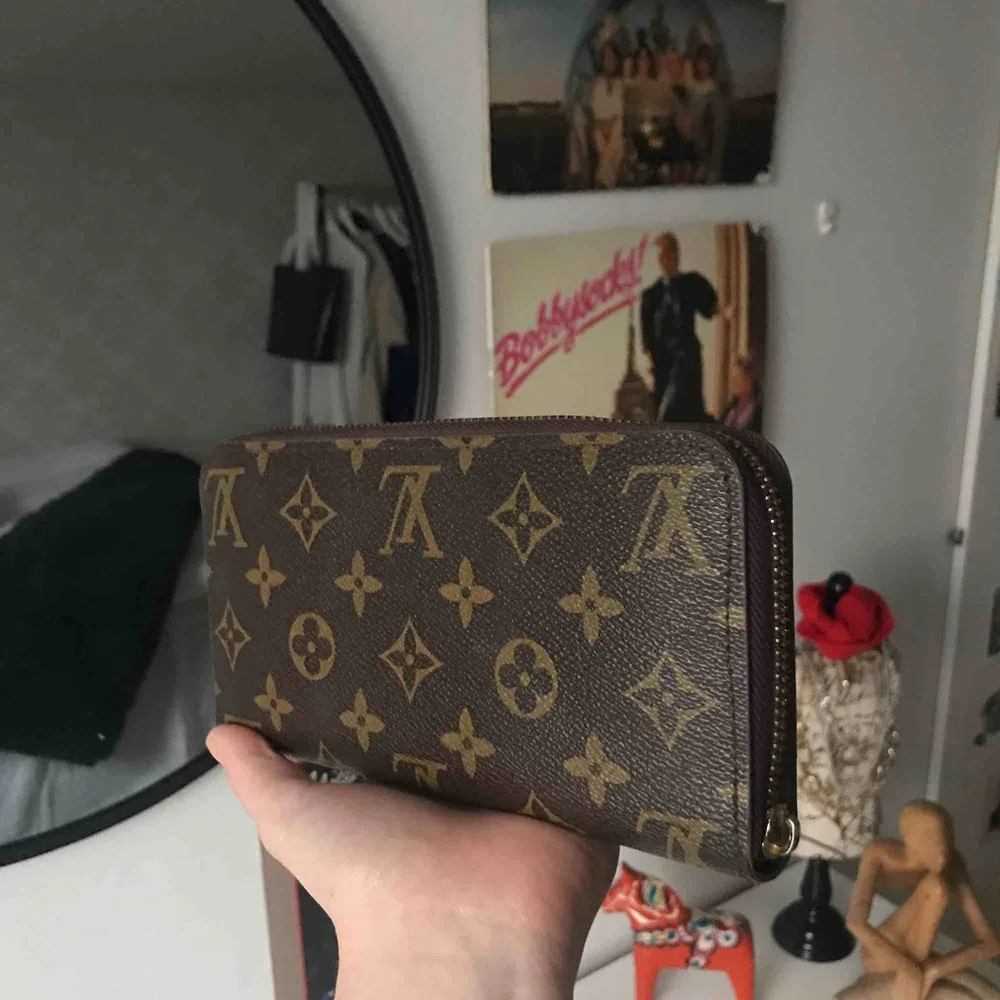 Super fin fake Louis Vuitton plånbok. Super bra skicka förutom att den inte har något spänne till dragkedjan, funkar ändå bra att stänga och öppna. Priset kan diskuteras.. Övrigt.
