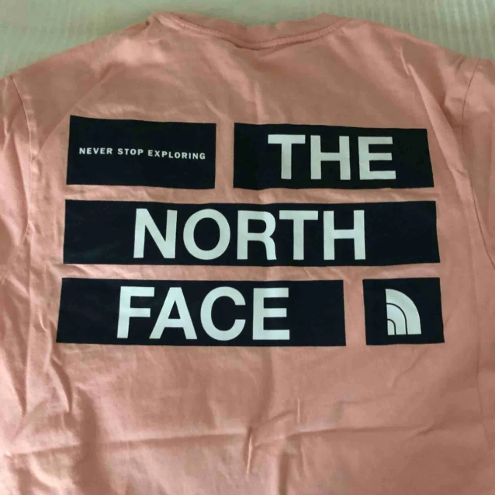 En rosa North Face t shirt med print på ryggen och bröstet. . T-shirts.