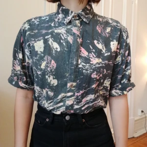  - Snygg kortärmad retro skjorta med svart/rosa/gult mönster. Påminner om en oljemålning typ. Den är trippy och nice iaf. Ser ut som att det fattas knappar på bilderna, men det gör det inte. Orkade bara inte knäppa hela vägen 😅