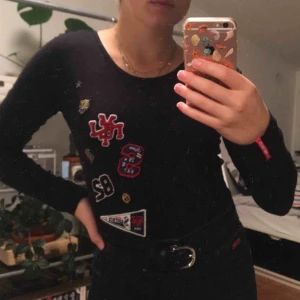  - En svart långärmad body med tryckta märken. Väldigt lite använd, bra skick. Från Superdry. 96% bomull. Priset är inkluderat frakt.