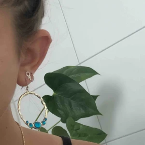  - Ett par guldiga örhängen med fem turkosa stenar. Eller ett par guldiga örhängen med fem mörklila stenar. Gör självklart rent dem med alsolsprit innan jag säljer dem! De kostar 100kr var!