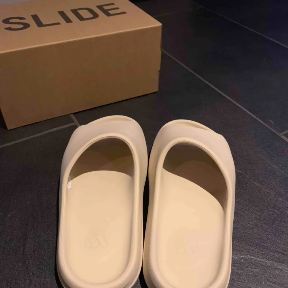 Adidas Yeezy Slides ”Bone” colourway. De är endast testade inomhus. Dom är lite små i storleken så ska passa 43-44. . Skor.