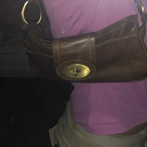 Brun miniväska - Jättesöt brun baugetteväska med gulddetaljer, som jag inte får användning för. Materialet är fakeläder och jag har använt den kanske 2 gånger 🤎