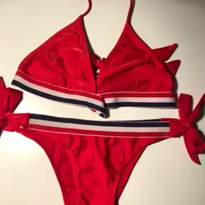 Röd bikini med blå och vita detaljer. Köptes inför en utlandsresa och använde en gång, därefter har den ej kommit till användning. 
