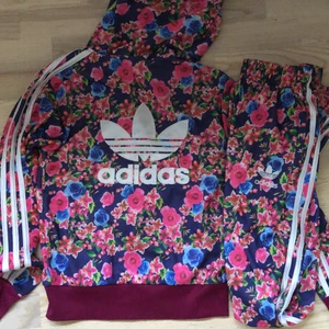 Blommigt Adidas set - Super fint blommigt fejk adidas set💕 Storlek är i M men skulle säga att den är men s/m då den är man kan anpassa storleken i midja på byxorna🌸 Det finns några mindre skador på setet, det är bara att kontakt om frågor eller fler bilder🥰