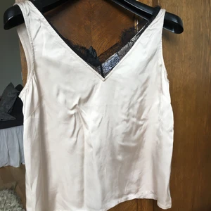 Linne siden med spets  - V-ringat linne i beige skimrande färg med kontrasterande svart spets. Ger en lite lyxig känsla...