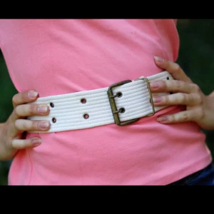 Vitt tygbälte m bronsfärgade detaljer - Vitt, bekvämt & behändigt tygbälte med bronsfärgade detaljer från 80-talet. Använt skick, några enstaka fläckar (bör gå bort vid punktrengöring), har lagat fästet till spännet själv. Kan skickas (mot att köparen betalar frakten). Betalning via swish.