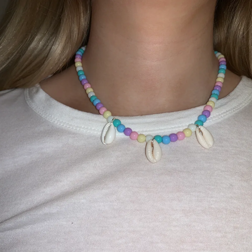 Flerfärgat pärlhalsband med snäckor🤍💞🐚💙💜💛 halsbandet försluts med lås och tråden är elastisk . Accessoarer.