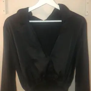 En svart skjorta/blus med silkesmaterial. Är tight längst ner med resårband.