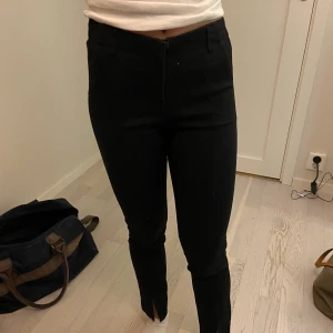 Kostymbyxor med slits - Ett par svarta kostymbyxor med slits och söm längs benen.