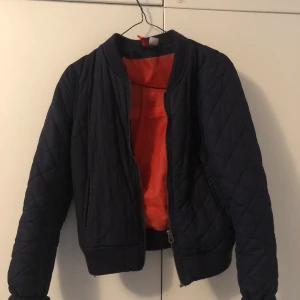 Navyblue bomberjacket H&M - Mörkblå bombarjacka med orange insida från H&M. Passar bra till vår/höst i strl 34! 