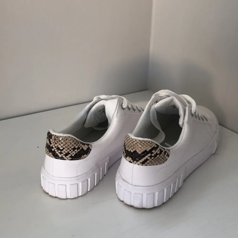 Vita supersnygga sneakers från Bershka med ormskinnsdetaljer, storlek 39. Använda 1 gång men små i storleken. Nypris 500kr, säljs för 200!!. Skor.