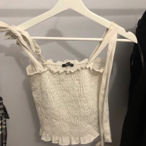 Skit gulligt vitt linne - Som sagt ett skit gulligt o fint vitt linne! Som man kan knyta vid axelbanden men man kan inte justera längden på dem. (Ser ut som att den har en fläck på bild 2, men det har den inte, se bild 1) Bra skick, fin tröja men kommer ej till användning🤍Passar S