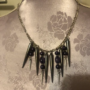 Med lila pärlor Halsband  - Handgjort halsband med lila detaljer. Mått 23 cm. Aldrig använd, i fint skick. Betalning sker via swish, jag skickat bild efter jag postat brevet. Jag är inte intresserad av byte 