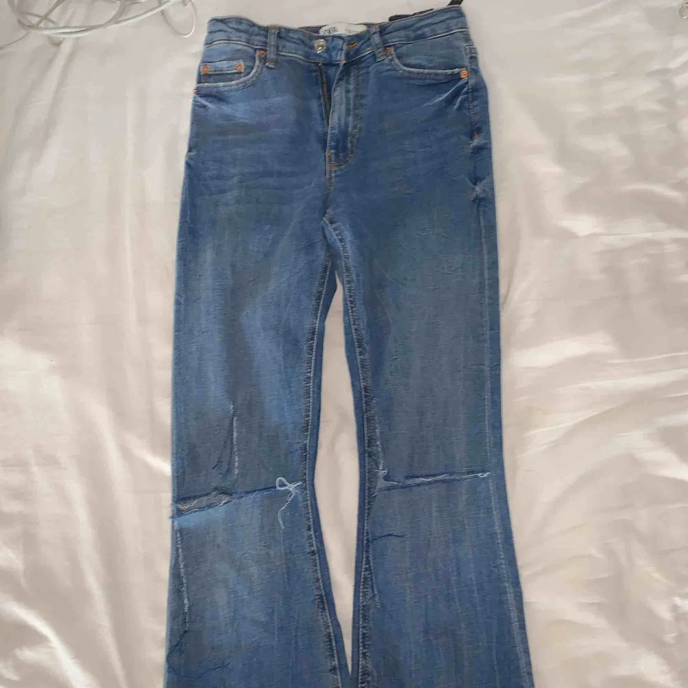 Blåa bootcut Jeans ifrån Zara med egenklippta hål på knäna. Oanvänt skick i ett skönt jeansmaterial.. Jeans & Byxor.
