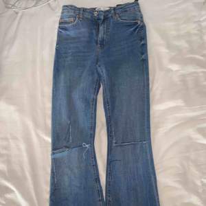 Blåa bootcut Jeans ifrån Zara med egenklippta hål på knäna. Oanvänt skick i ett skönt jeansmaterial.