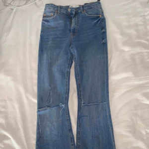  - Blåa bootcut Jeans ifrån Zara med egenklippta hål på knäna. Oanvänt skick i ett skönt jeansmaterial.
