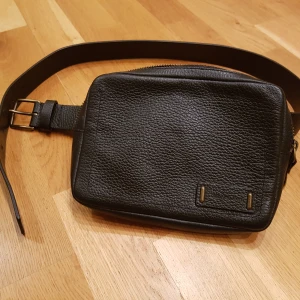 Calvin Klein midjeväska - Svart skinnväska från Calvin Klein med två fack inut. Helt oanvänd. 18x13x3cm