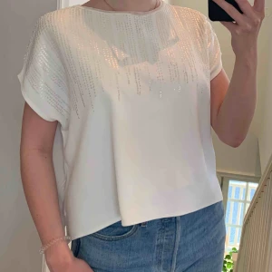  - Vit blus från Zara, jätteskönt material (stretchig) med glittriga/skimrande detaljer på framsidan. Frakt tillkommer.