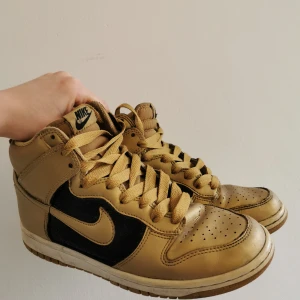 Nike-Sneakers. Gold/Black - Nike air Jordans/dunks i guld och svart i gott skick, några år på nacken men inte särskilt använda. Dam, storlek 38 (US 7). 