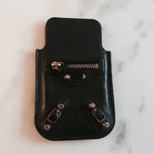  - Balenciaga iPhone holder. Svart med guldiga nitar. I väldigt bra skick. Gjort för iPhone 4. Funkar även till iPhone 5. 