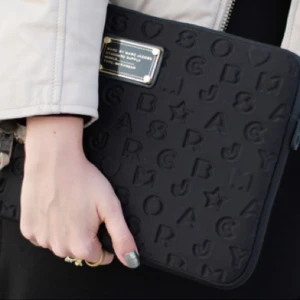  - Svart äkta Marc Jacobs datorfodral i storlek 13tum(ca.27cmx36cm). Den silvriga färgen på "skruvarna" på bild 2 har skrubbats av lite. Dessutom har den svarta färgen skrapats av på dragkedjan(bild3). Mycket fint skick annars. Nypris 599kr