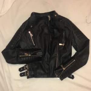 Svart Skinnjacka chiquelle  - Säljer min superduper snygga trendiga fejk skinnjacka ifrån chiquelle då den tyvärr inte kommer till användning längre. Superbra skick och ser nästan oanvänd ut. Bara ett hål i högra armen på insidan men det är lätt att sy igen! Annars superfin🙌🏻 storlek 38 jättesnygg passform!!! köpt för 600-700kr 