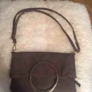  - Chokladbrun fin väska, Ulrika, fina gulddetaljer, kan bäras på många sätt! Magnetisk knäppning = kan vikas på mitten. Två fack på ena sidan och på andra ett lika stort fack (som de två) med dragkedja. I fint skick, som ny. Nypris ca 500 kr
