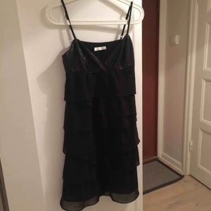  - Svart klänning med paljettdetaljer och volanger. 