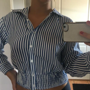 Skjortblus från Pull&Bear strl M - Blå vit randig skjortblus med resår längst ner. Använd fåtal gånger.                                                        Köpare står för frakt:)