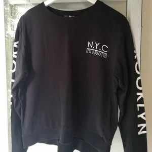 Sweatshirt - Tunn sweatshirt i svart. Ärmarna har texten "Brooklyn" på ena, och "New York" på andra. Frakt tillkommer