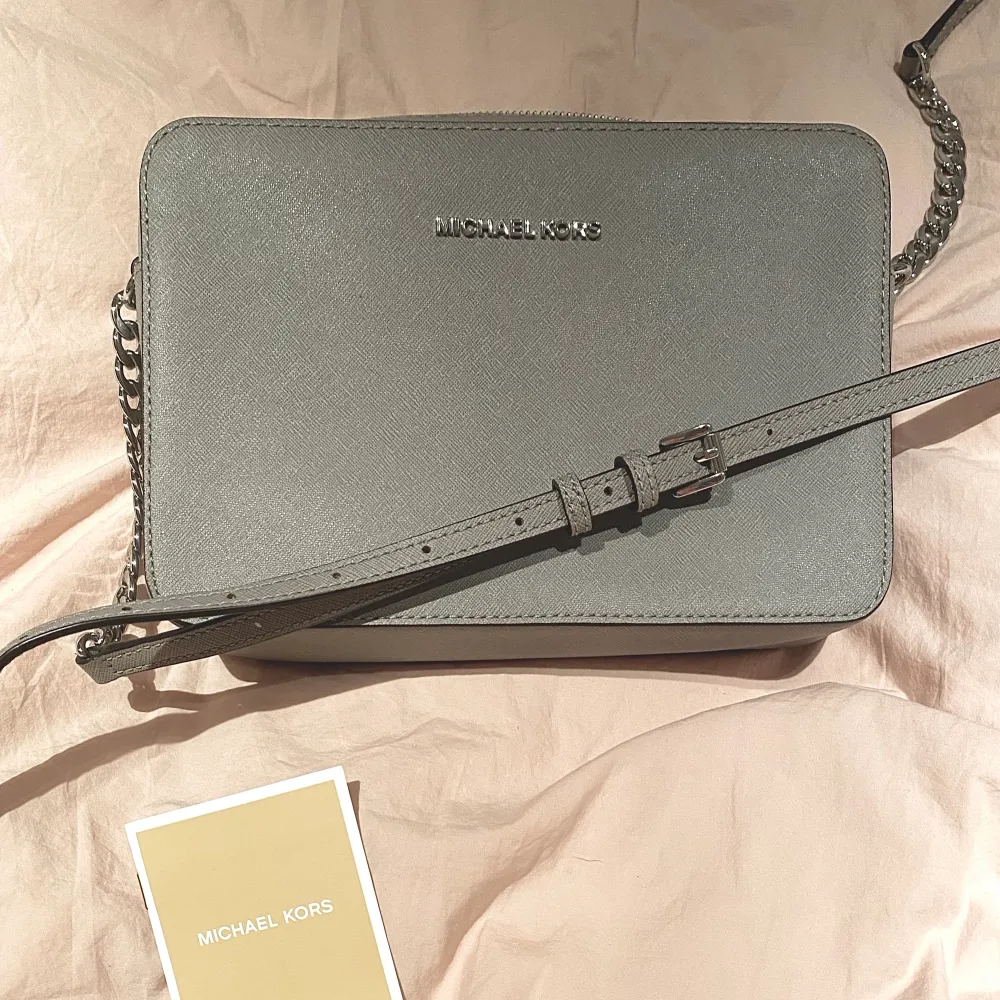 Michael Kors vintage crossbody väska. Endast använd enstaka gånger. Superfint skick. För fler bilder, skriv! • 100% Saffiano Leather • Silver-toned grey • 22.86 x 10.16 x 2.54 cm • Justerbar rem • Tre slitsfickor • Pris är förhandlingsbart . Laukut & Käsilaukut.