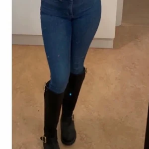 Urban Projct  - Svarta stövlar med gulddetaljer från Urban Project. Dragkedja på baksidan samt spännen på sidorna. Köptes för 1 år sen för 2300kr, använda max 3 gånger, som nya. Köparen står för frakten.