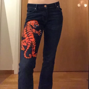 Lösa jeans med tiger målad - Ett par otroligt sköna byxor med en tiger målad av mig i akryl, lackad för extra skydd. Byxorna är använda en gång och är tidigare köpta på tradera (sellpy) dock utan några tecken på trasigheter. Skulle rekommendera att tvätta för hand😊