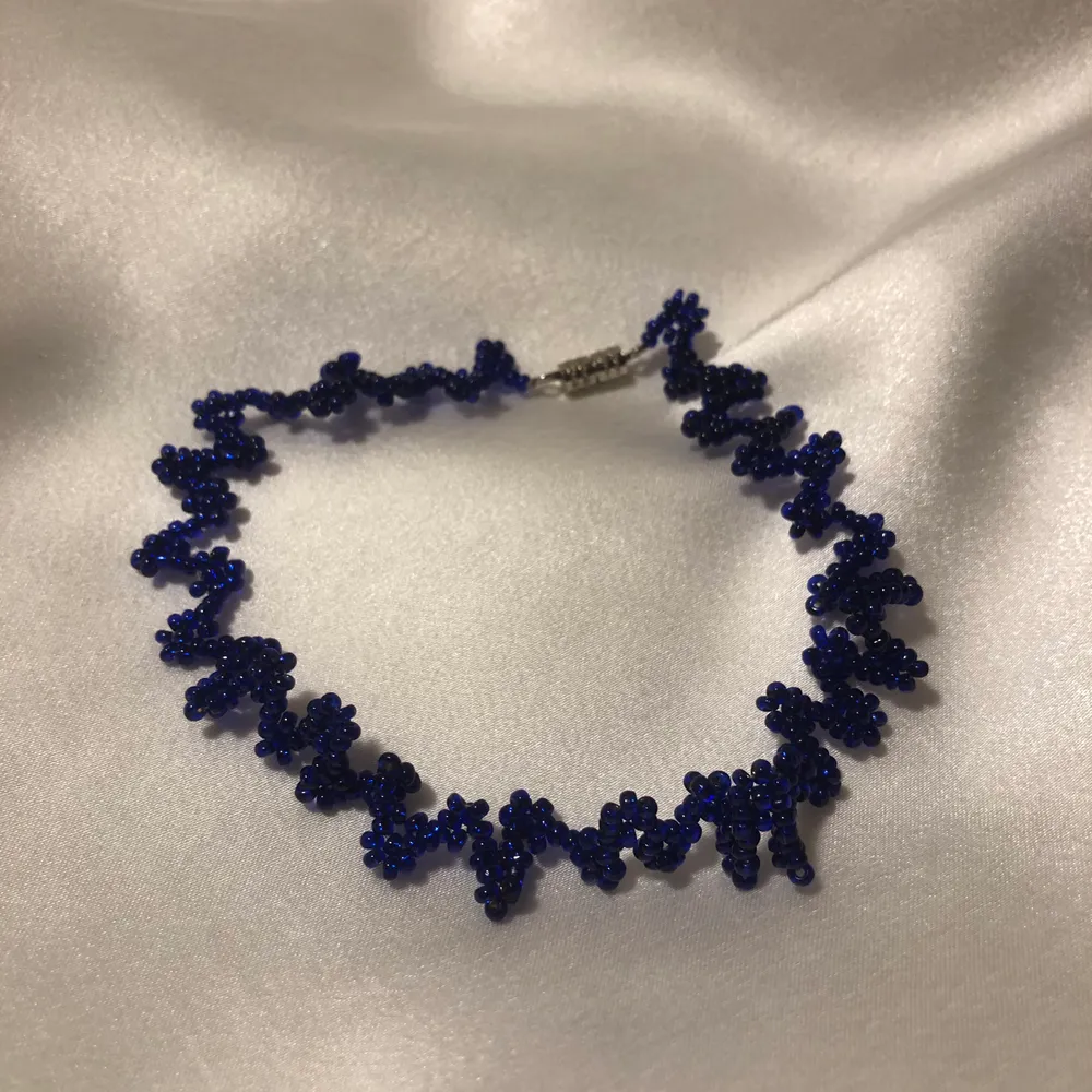 Supercoolt halsband i chokermodell med zigzag och blommönster i fina blåa beads! One-of-a-kind och piffar upp alla outfits🥰. Accessoarer.