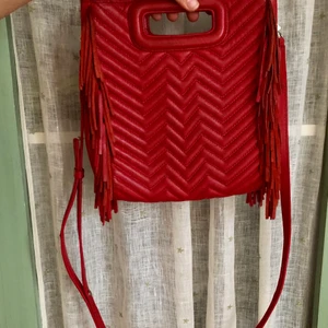 Maje väska  - Maje quilted leather M bag i röd. Superball röd fransväska köpt i maje butiken på NK!Väskan är använd men i fint skick. Dessvärre är loggan mer sliten (se sista bilden) därav det lägre priset. Dustbag och medföljande strap medkommer! Nypris ca 2400kr :)