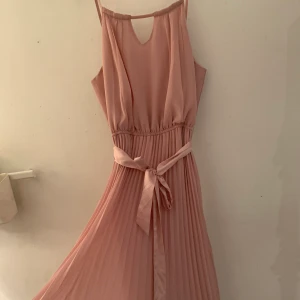 Långklänning  - Hejsan nu säljer jag denna fina aftonsklännigen. En långklänning jag är 162,5 typ och den är lite smått på marken inte mycket men lite, den är i bra skick används några gånger. Detta sidenbälte/snöret går knyta upp och göra en ny rosett. Jättefin ganska luftig har en ”underkjol”. Lite läppstift på bandet men absolut inget man märker. Den är gammelrosa lite gris rosa💕💕💕 frakten är ej gratis men vi kan ta de då💕💕