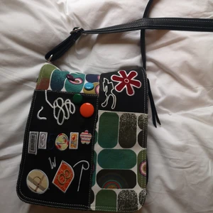 Färgglad väska - En läderväska med detaljer. Köpt secondhand. Den rymmer många saker och tyvärr är den lite sliten innuti men inget märkvärdigt. 