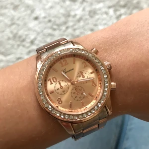 Fin rosé guld klocka med strass - Jättefin klocka i rosé guld som ej kommer till användning. Klockan kom med extra länkar på, därför är armbandet väldigt stor just nu, men dessa kan enkelt plockas av. Behöver batteribyte. Därav lågt pris. Frakt tillkommer :)