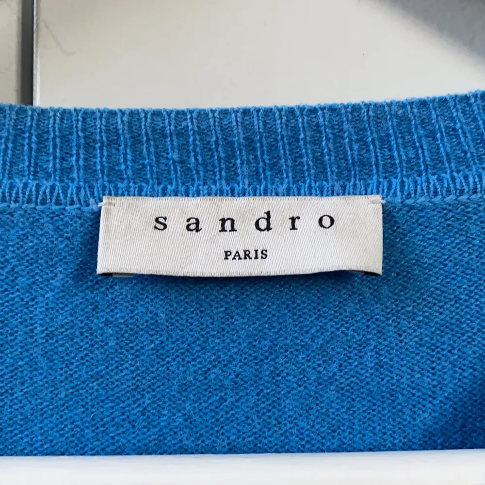 Säljer denna jätte fina Sandro tröja i en fin blå färg. Köpt för 2500kr startbud 1000kr💙💙 ledande bud är 2600.  Tröjan jag två små stygn men de syns knappt!. Tröjor & Koftor.