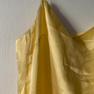 Gul sidenklänning  - Sidenklänning köpt förra året för 1000kr som är oanvänd och kappan är kvar. Klänningen har två slitsar längst ner, hör gärna av dig om frågor! ❤️