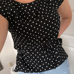 Prickig topp  - Oanvänd svart prickig topp med knytning, bandet går att ta av om så skulle önskas. Kom pm vid fler bilder eller andra frågor. Storlek 38 men passar mig som har 36 med 