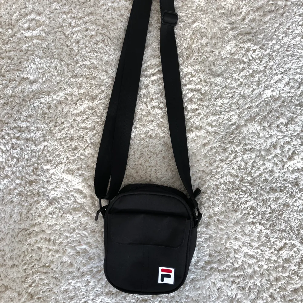 En svart axelbandsväska från fila med 4 utrymmen för förvaring. Väskan har en hård struktur så den har fortfarande fin form när den inte har något i sig. Endast använd ett par gånger och o fint skick. Frakt tillkommer . Väskor.