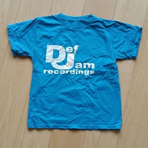 Def Jam t-shirt, merch, S - Blå t-shirt med Def Jam recordings tryck, fint skick, storlek S, sitter tight på mig som brukar ha S. Jag är 177 cm och väger 66 kg.