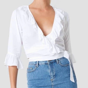 Linn Ahlborg x NA-KD, Omlottblus - Linn Ahlborg x NA-KD, Omlottblus, Strl: 40, ”Ruffle Wrap Blouse”. Använd ett fåtal gånger, skönt material, lite tunnare. 100kr ink frakt med frimärken.