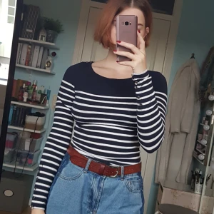  - Mörkblå och vitrandig långärmad tröja med små guldiga knappar på ena axeln och vid handlederna