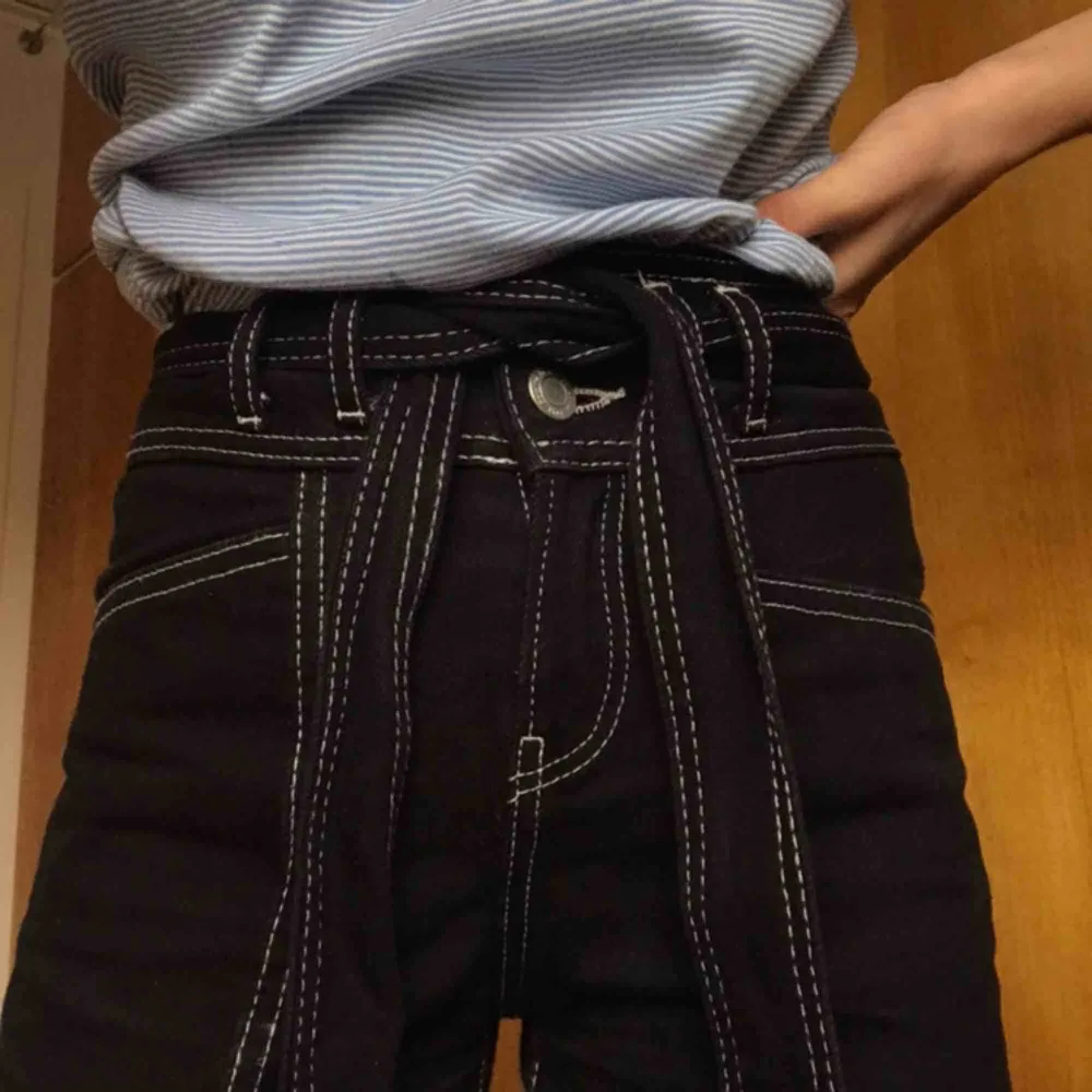 Assnygga svarta jeans med vita sömmar och borttagbart skärp. Nyskick! Säljer eftersom de är för små för mig :/ Frakt ingår!. Jeans & Byxor.