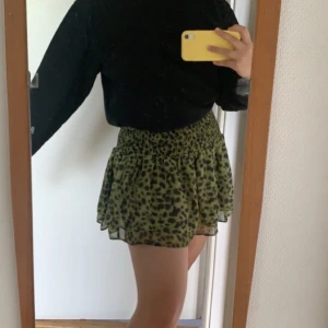 Grön miniskirt med leopardprint - Väldigt stretchig volangkjol med smock från H&M i storlek S, använd en gång och i bra skick. Passar nog alla från S-M!