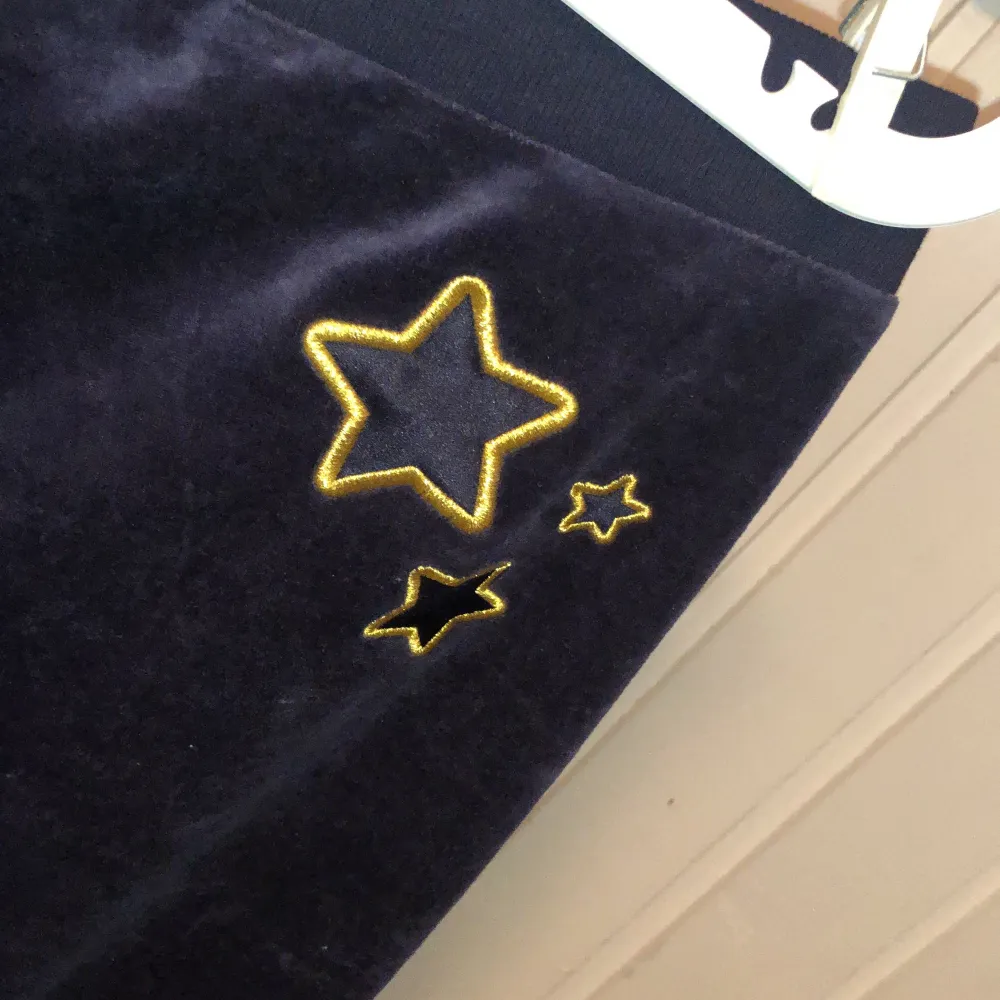 Marinblå med lila underton. Guldiga deltaljer med två broderade guldstjärnor på baksidan. . Jeans & Byxor.